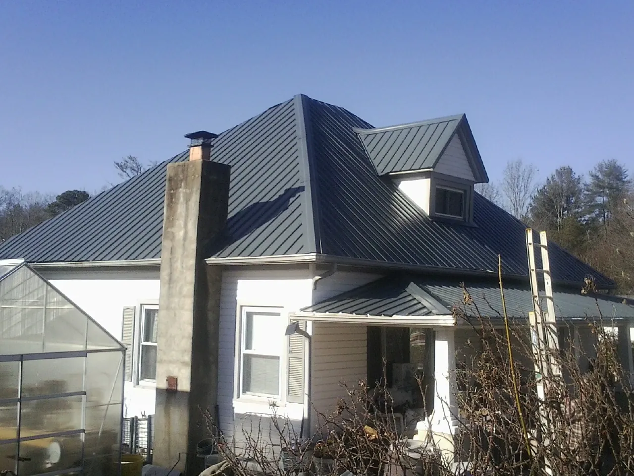 Dark blue standing seam metal roof on a white farmhouse with dormer — Slate & Tile Roof Repair by Roofing Brothers in Walters