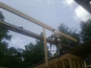 Carpenter setting a ridge beam over a new addition frame — Ice Dam Removal by Roofing Brothers in Walters