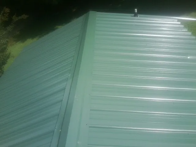 New green metal panels meeting at the ridge of a roof — Flat Roof Repair work by our crew in Walters