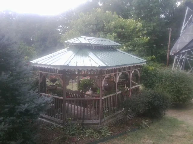 Green metal roof on a backyard gazebo surrounded by garden beds in Walters