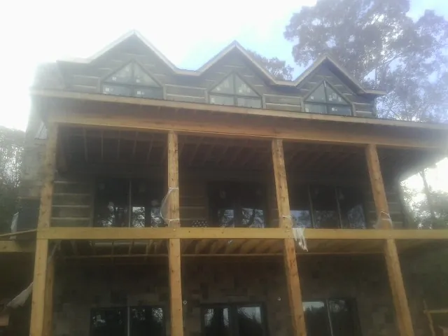 Dormers and porch framing on a large log home under construction — Roof Coating work by our crew in Walters