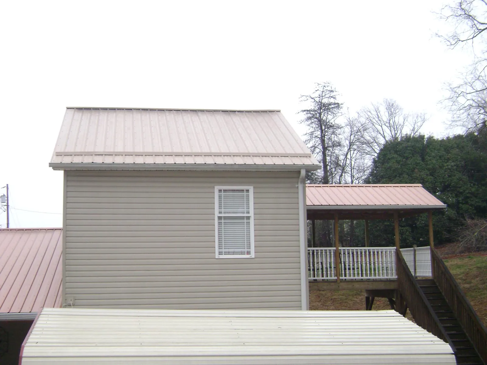 Tan metal roofs on a two story addition and attached porch, from a Roof Replacement job in Walters