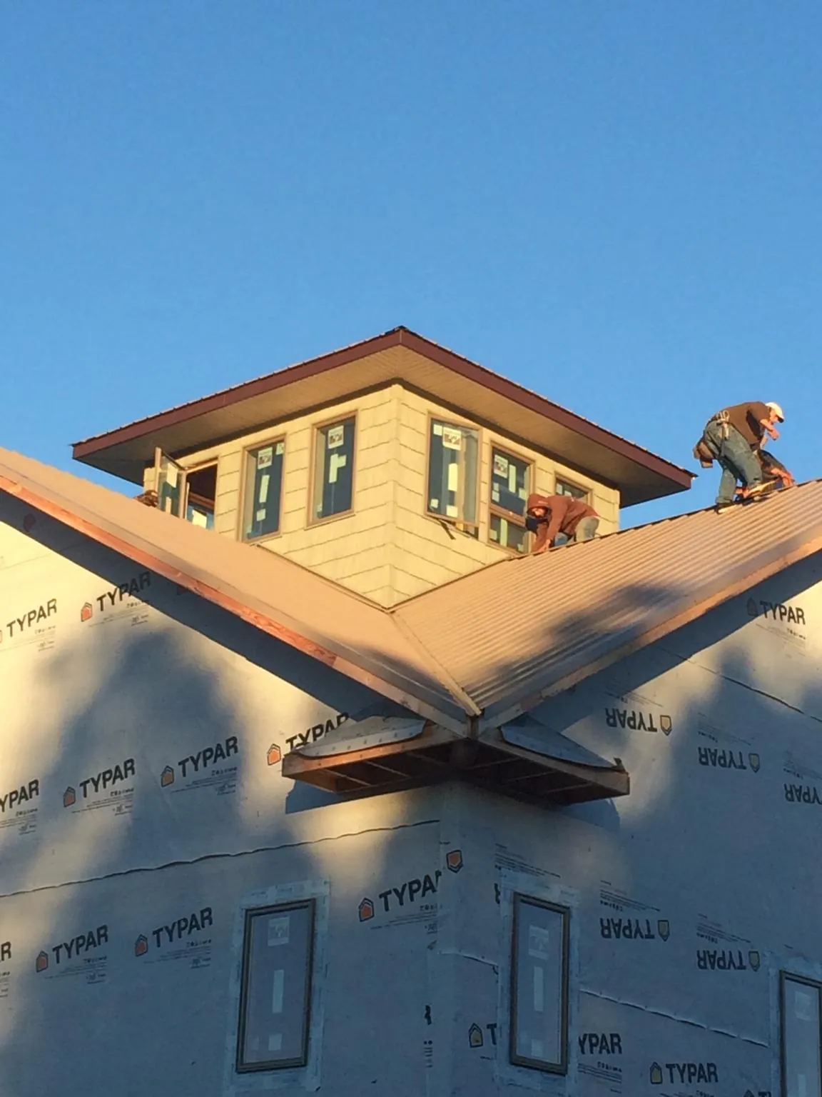 Roofers working around a rooftop cupola on a new metal roof at sunset — Roof Waterproofing in Walters by Roofing Brothers
